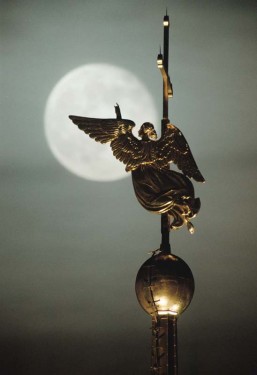 Gold-plated ahgel on spire of St.Peter and Poul cathedral in St.Petersburg against the background of the moon.